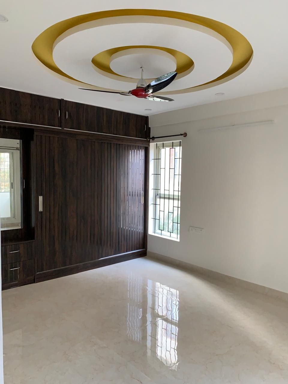 Bedroom with espresso slatted sliding wardrobe and gold-ring false ceiling
