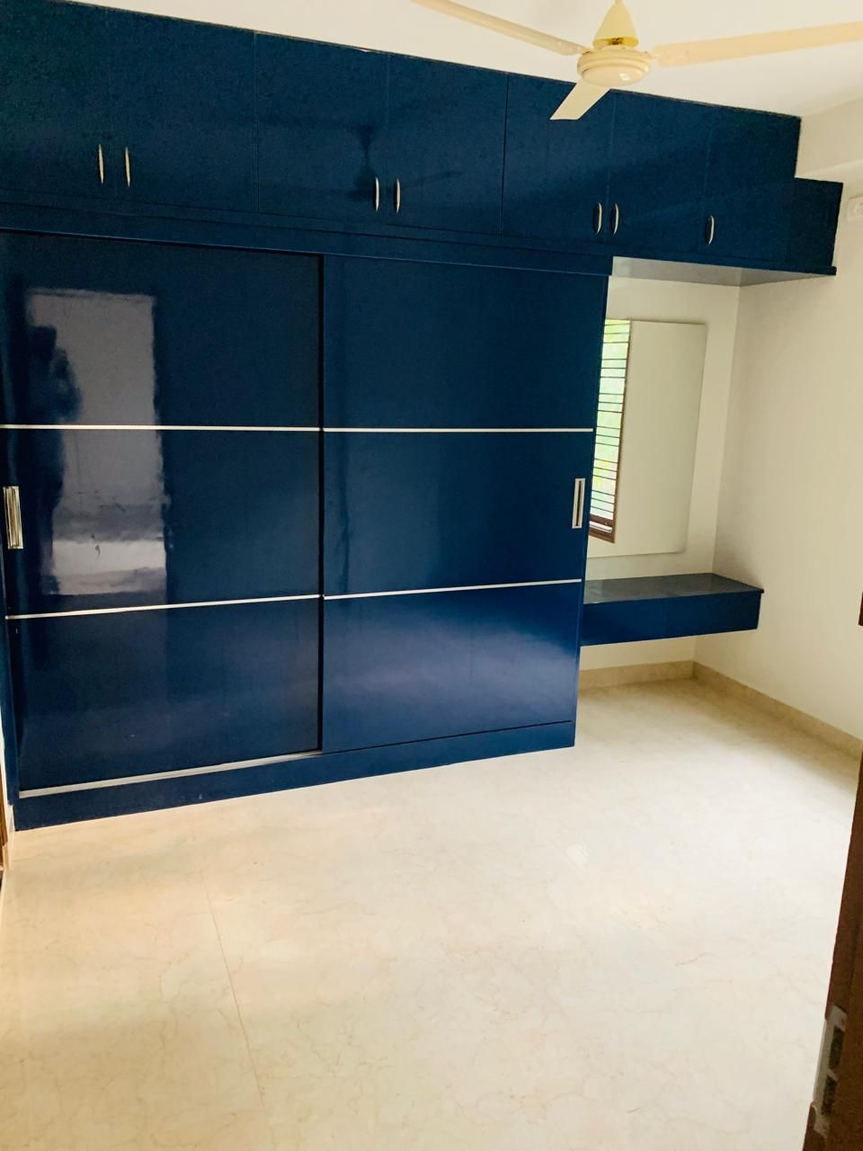 Bedroom with blue high-gloss sliding wardrobe and dresser nook