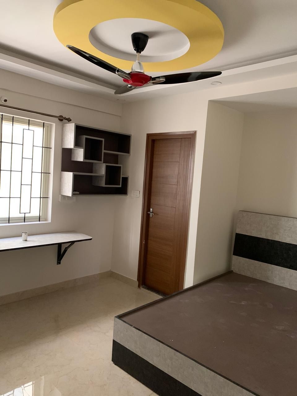 Bedroom with geometric wall shelves, study table and platform bed