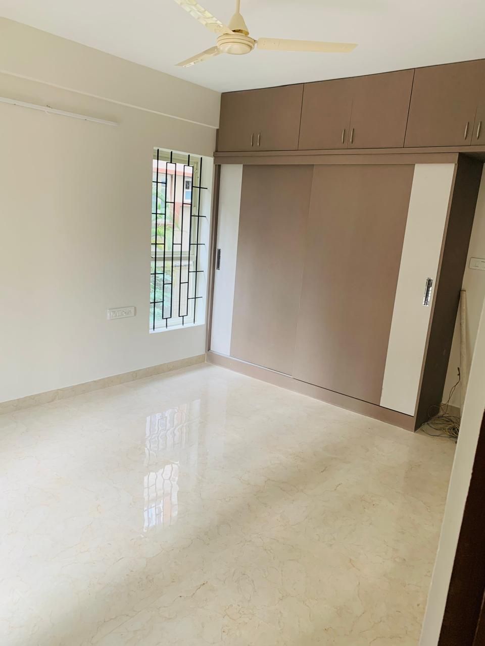 Bedroom with taupe sliding wardrobe and overhead storage cabinets