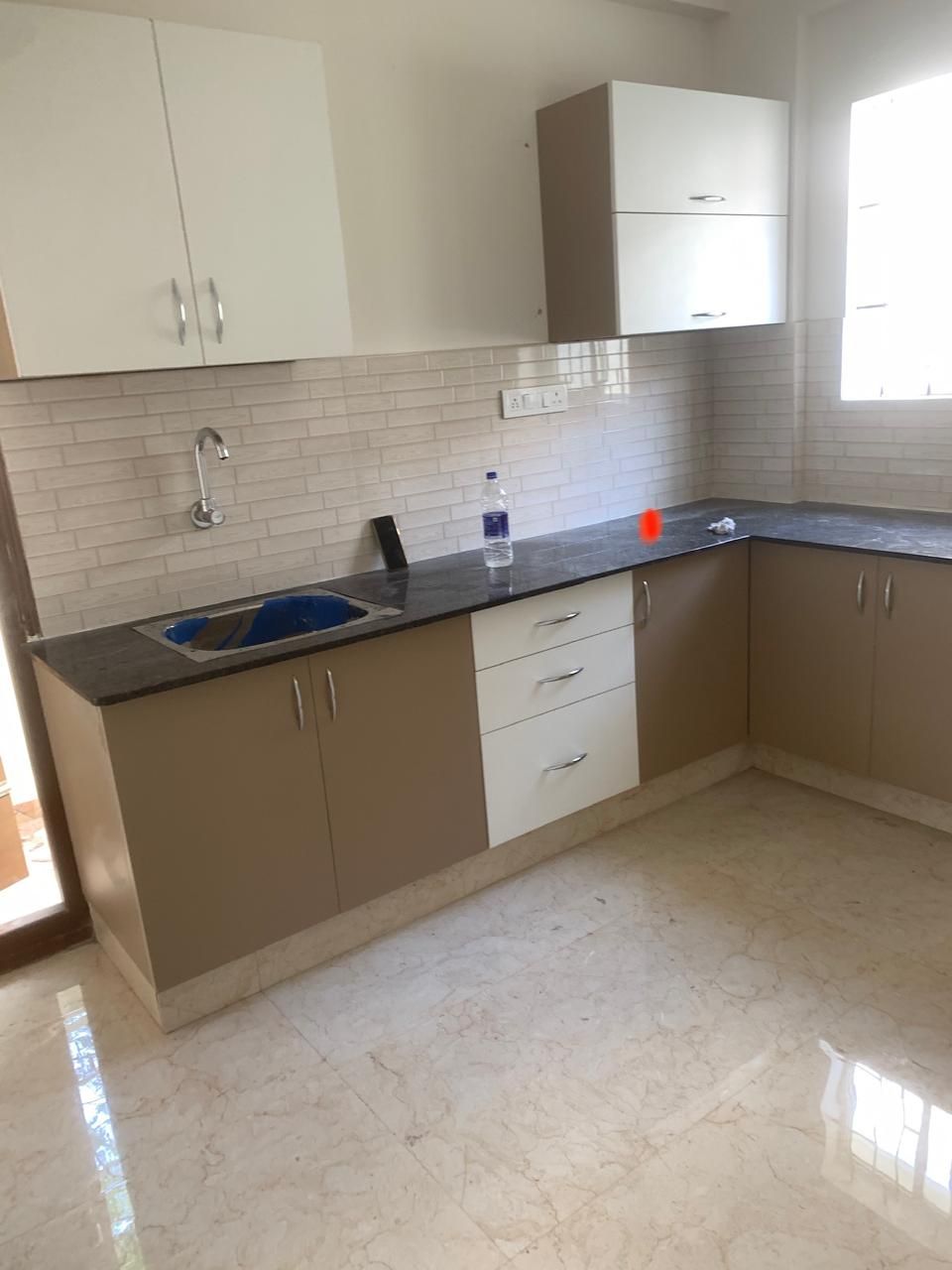 Beige L-shaped modular kitchen with black granite and subway tile